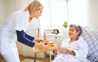 caregiver giving meal to senior woman